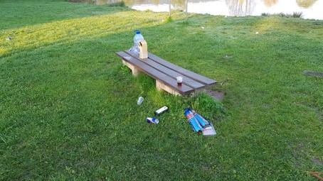 Leere Glas- und Plastikflaschen und mehrere Plastikbecher über das Seeufer verstreut